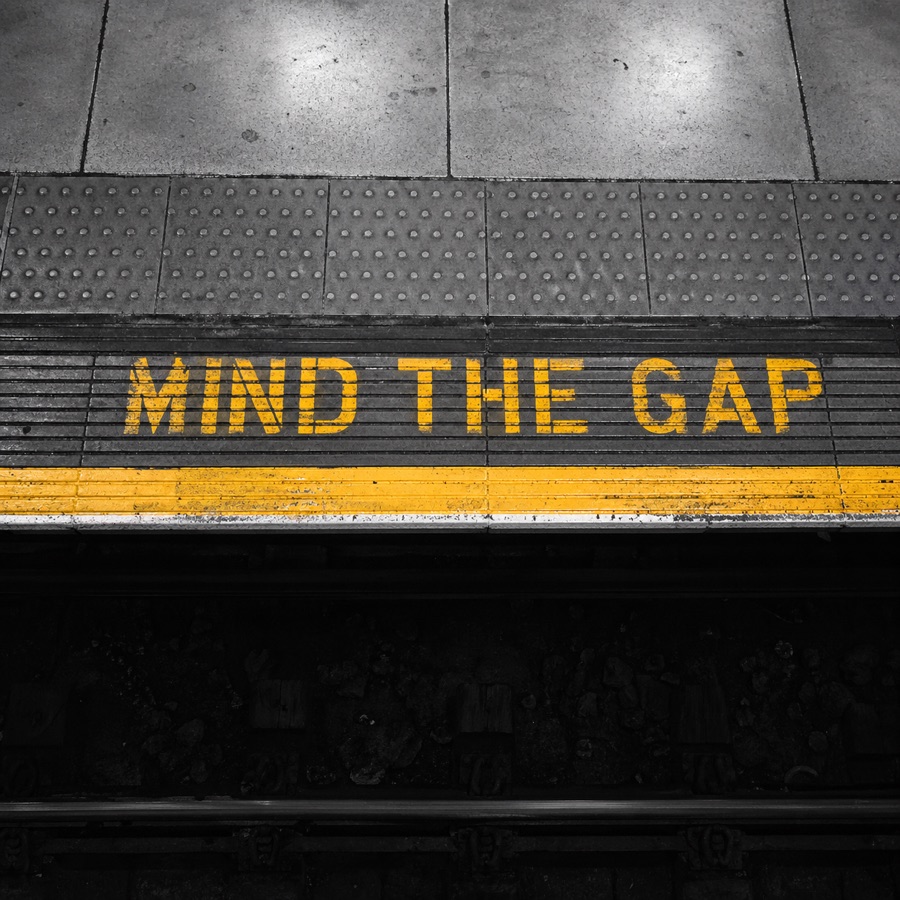 A subway platform edge painted with the words 'Mind the Gap'.